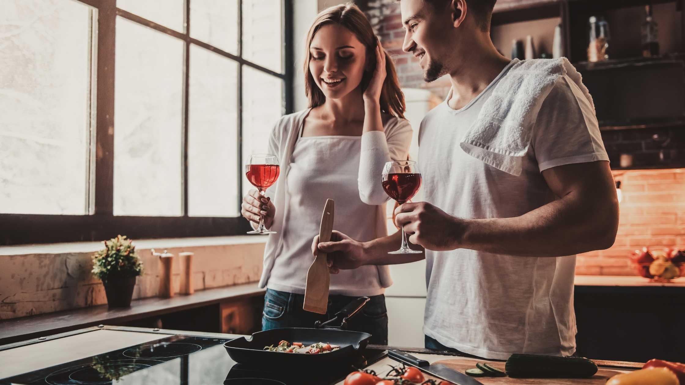 Couples cooking at home with wine in hand